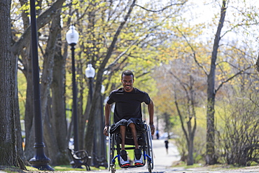 Man in a wheelchair who had Spinal Meningitis going through a park