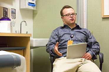 Hospital aid worker with Down Syndrome using a tablet in office