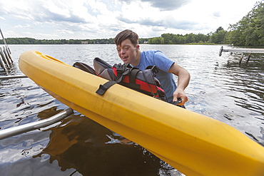 Young man with Down Syndrome preparing to use a kayak in a lake