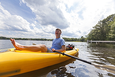 Happy young man with Down Syndrome rowing a kayak in a lake