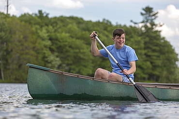 Young man with Down Syndrome rowing a canoe in a lake