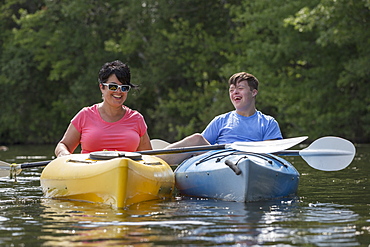 Young man with Down Syndrome kayaking with his friend in a lake