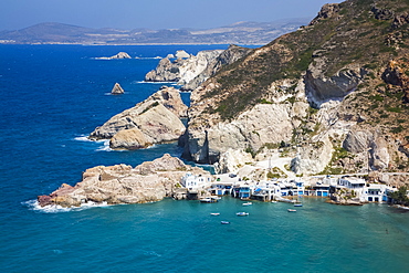 Fyropotamos Village with boats in the small harbour and a view of the rugged coastline; Fyropatamos, Milos Island, Cyclades, Greece