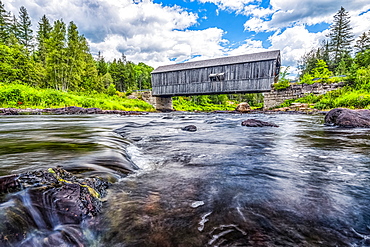 Historic covered bridge over a shallow stream; Saint John, New Brunswick, Canada