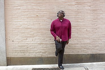 Man with ADHD standing against a wall listening music