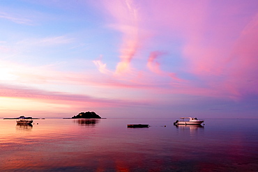 Sunrise over the South Pacific with boats anchored off the shore; Malolo Island, Fiji
