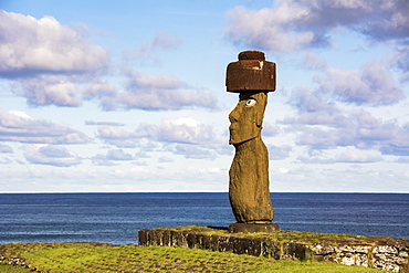 A single moai on a blue background of sky, clouds and ocean; Easter Island, Chile