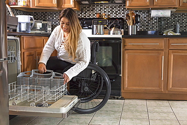 Woman with Spinal Cord Injury arranging dishwasher