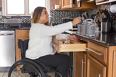 Woman with Spinal Cord Injury arranging dishwasher