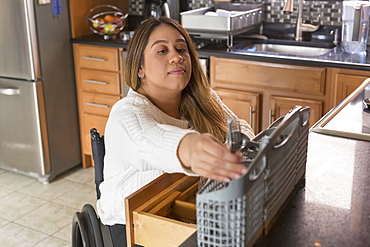 Woman with Spinal Cord Injury arranging dishwasher