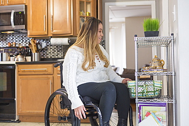 Woman with Spinal Cord Injury arranging things in her kitchen