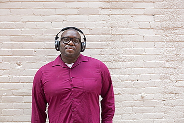 Man with ADHD standing against a wall listening music