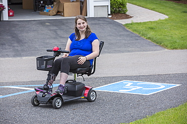 Young Woman with Cerebral Palsy in her scooter with disability parking