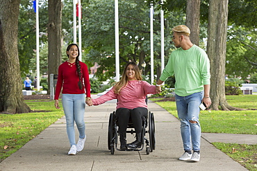 Woman who has Spinal Cord Injury walking with siblings in park