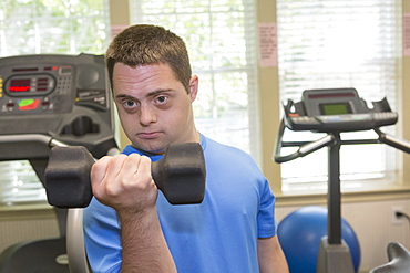 Man with Down Syndrome exercising in a gym with dumbbell