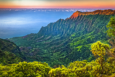 View of Na Pali Coast and Kalalau Valley from Pu’u O Kila Lookout, sunset glow on the rugged cliff, Koke'e State Park; Kauai, Hawaii, United States of America