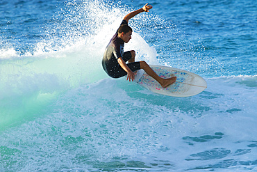 Surfer riding a turquoise wave off the North shore of Oahu; Oahu, Hawaii, United States of America