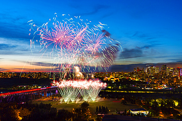 Fireworks in a city at dusk; Alberta, Canada