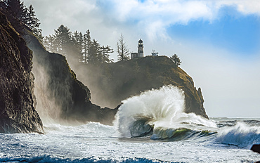 Cape Disappointment Light with large waves crashing in onto the beach below, Cape Disappointment; Washington, United States of America