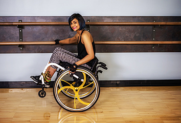 A paraplegic woman popping wheelie in her wheelchair and fooling around in a gymnasium after working out at a fitness facility: Sherwood Park, Alberta, Canada