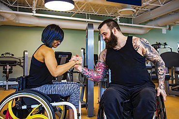 Two paraplegic friends pretending to arm wrestle after working out at a fitness facility: Sherwood Park, Alberta, Canada