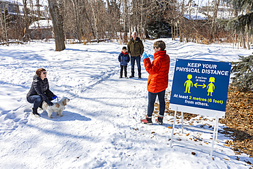 Families stand to visit at a distance on a path through a park during the Covid-19 world pandemic; St. Albert, Alberta, Canada