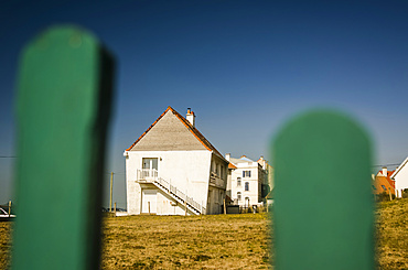 White house seen through green fence posts in Northern France; Ambleteuse, Pas de Calais, France