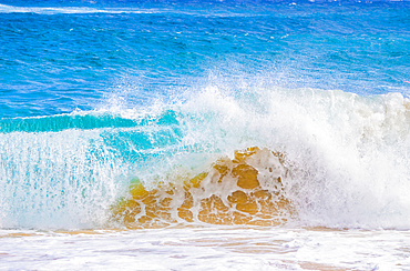 Splashing waves along the shore of golden sand; Oahu, Hawaii, United States of America