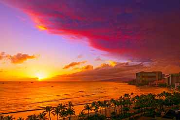 Waikiki Beach in vibrant colours at sunset with a dramatic glowing cloud formation overhead; Honolulu, Oahu, Hawaii, United States of America