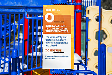 A sign at a playground cordoned off with caution tape during the COVID-19 World Pandemic; Edmonton, Alberta, Canada