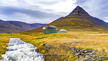 Weathered structures on a remote landscape beside a rushing river; Isafjardarbaer, Westfjords, Iceland