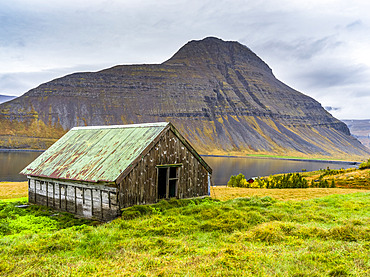 Weathered building on the water's edge of a fjord in Northwestern Iceland in the municipality of Isafjarourbaer; Isafjarourbaer, Westfjords Region, Iceland