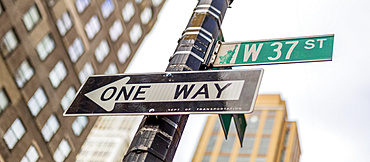 Street signs on a post, a directional one way and West 37th Street, Manhattan; New York City, New York, United States of America