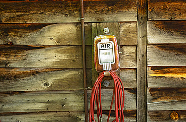 Vintage air pump with hose mounted to a wooden wall; United States of America