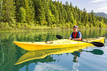 A teenage boy kayaking on White Lake, White Lake Provincial Park; British Columbia, Canada