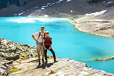 Female and Male hiker on rocky ridge with blue alpine lake in the background, Yoho National Park; Field, British Columbia, Canada