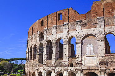 Close-up view of the iconic Colosseum against a blue sky, showing a marble plaque  above the East Entrance dedicated to Christian martyrs; Rome, Lazio, Italy