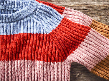 Striped sweaters on display on a wooden table; Studio