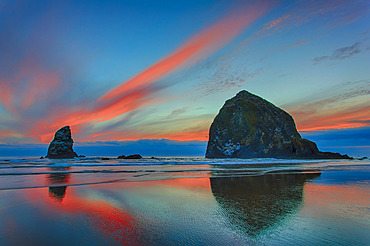 Dramatic sunset light in clouds over beach and rock formations on the Oregon coast; Cannon Beach, Oregon, United States of America