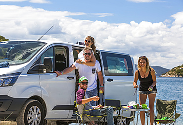 Friends standing next to camper van making lunch as they stop at Slano to enjoy a day at the beach; Slano, Dubrovnik-Neretva County (Dubrovačko-neretvanska županija), Croatia