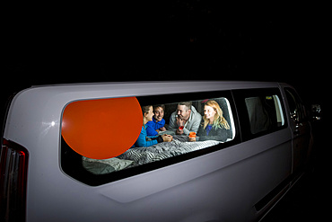 Group of travelers huddled inside their camper van playing games for the evening, free camping in the German city of Kassel; Kassel, Germany