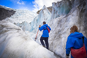 Travelers exploring the famous Franz Josef Glacier with its, blue ice caves, deep crevasses and tunnels that mark the ever changing ice formations; West Coast, New Zealand