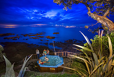 Travellers enjoy a spa pool located on the Eastern Cape shoreline of New Zealand; Te Kaha, Bay Of Plenty, New Zealand