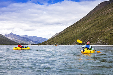 One woman paddling, one floating their yellow packraft boats downriver towards man in blue boat in background on a sunny, summer day on the Marsh Fork river;  Brooks Range, Arctic National Wildlife Refuge (NWR), Alaska, USA