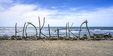 Sign made out of driftwood standing on Hokitika Beach; Hokitika, West Coast Region, South Island, New Zealand