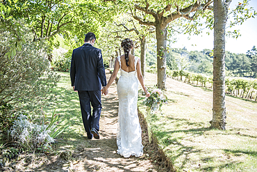 A bride and groom walk along hand in hand on their wedding day