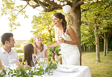 A bride and groom sitting at the top table with their friends at an outside wedding