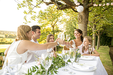 A bride and groom sitting at the top table with their friends at an outside wedding