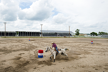 Teenage girl practices barrel racing with her horse, Burwell, Nebraska, United States of America