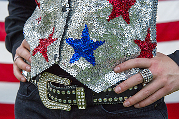 Close up of a rodeo queen's belt and sequined vest in front of an American flag, Burwell, Nebraska, United States of America